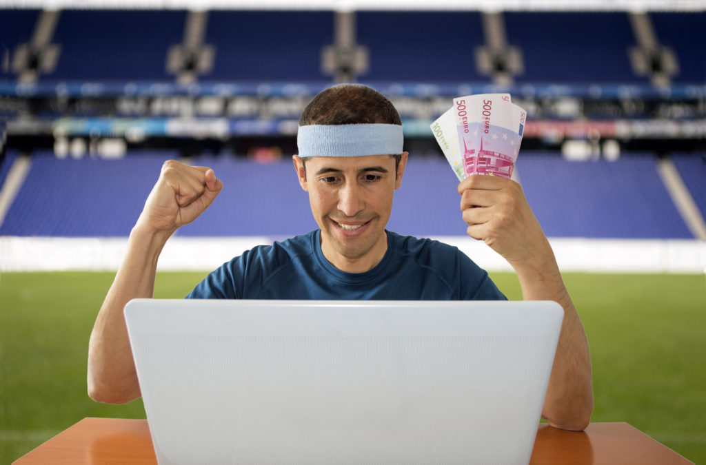 mand foran tennisbane med computer og pengesedler i hånden